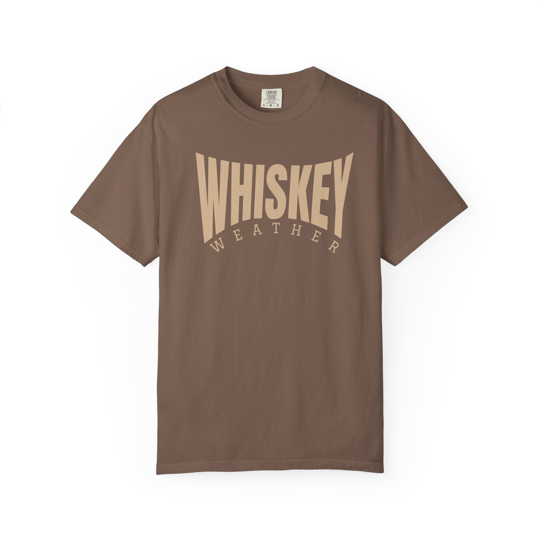 Whiskey Weather Tee: Chocolate-colored crew-neck t-shirt with WHISKEY WEATHER in bold cream font, offering cozy comfort and durability with its garment-dyed, ring-spun cotton fabric.