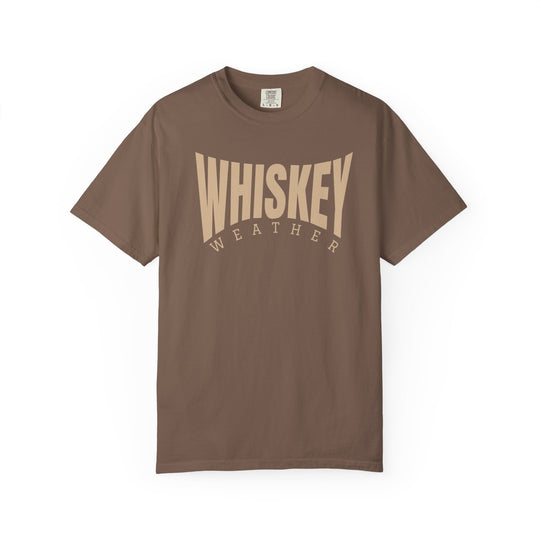 Whiskey Weather Tee: Chocolate-colored crew-neck t-shirt with WHISKEY WEATHER in bold cream font, offering cozy comfort and durability with its garment-dyed, ring-spun cotton fabric.