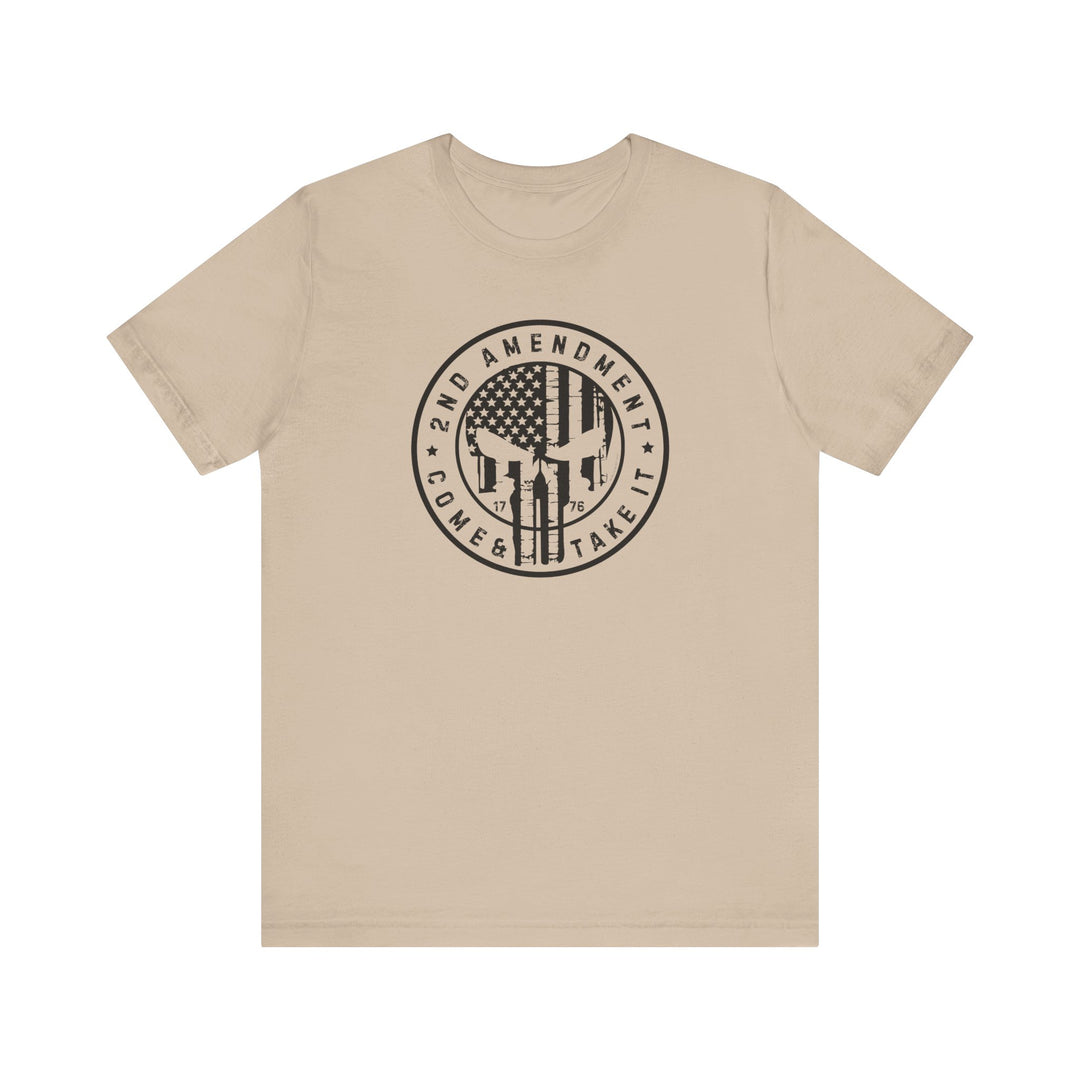 A tan unisex jersey tee featuring a graphic design with a flag and skull. 100% Airlume combed cotton, retail fit, tear away label. Title: 2nd Amendment Come and Take It Tee. Fits true to size.