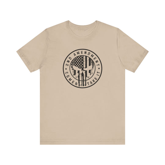 A tan unisex jersey tee featuring a graphic design with a flag and skull. 100% Airlume combed cotton, retail fit, tear away label. Title: 2nd Amendment Come and Take It Tee. Fits true to size.