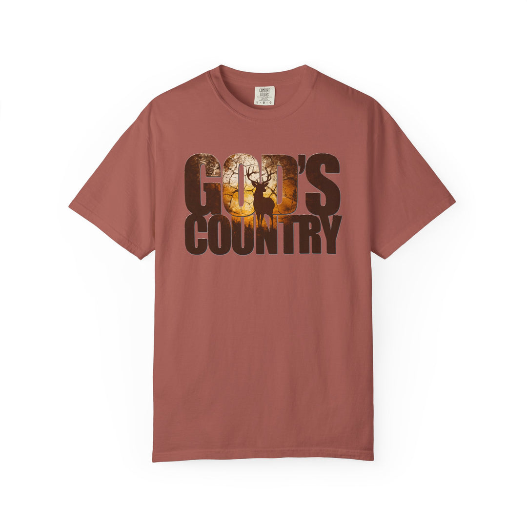God's Country Tee: Rust-colored, short-sleeve shirt featuring “GOD’S COUNTRY” with a sunset/woodland scene, including a silhouetted buck among trees. Comfortable, durable, and relaxed fit.