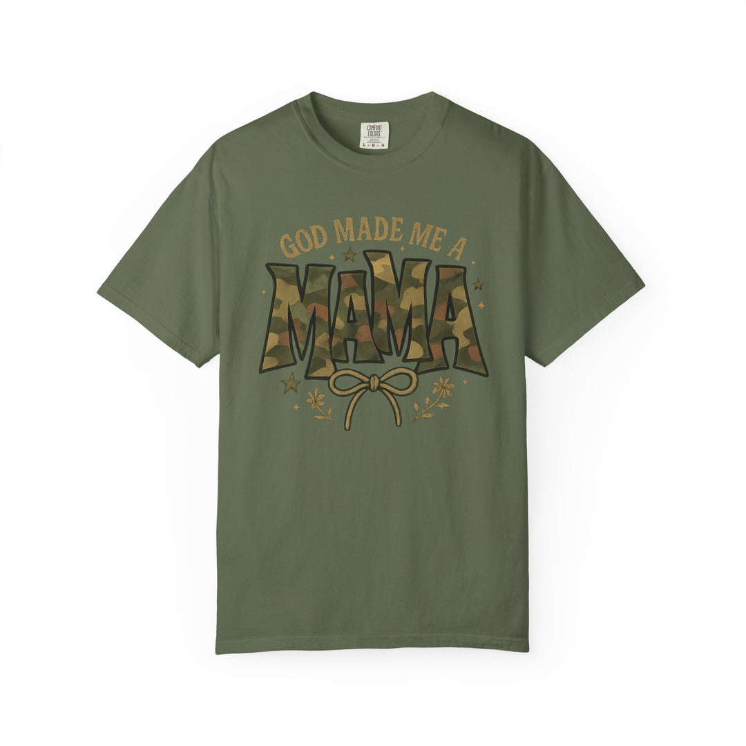God Made Me a Mama Tee features a woodland camo graphic and bow illustration on a Comfort Colors olive-green T-shirt, offering relaxed fit and durability.