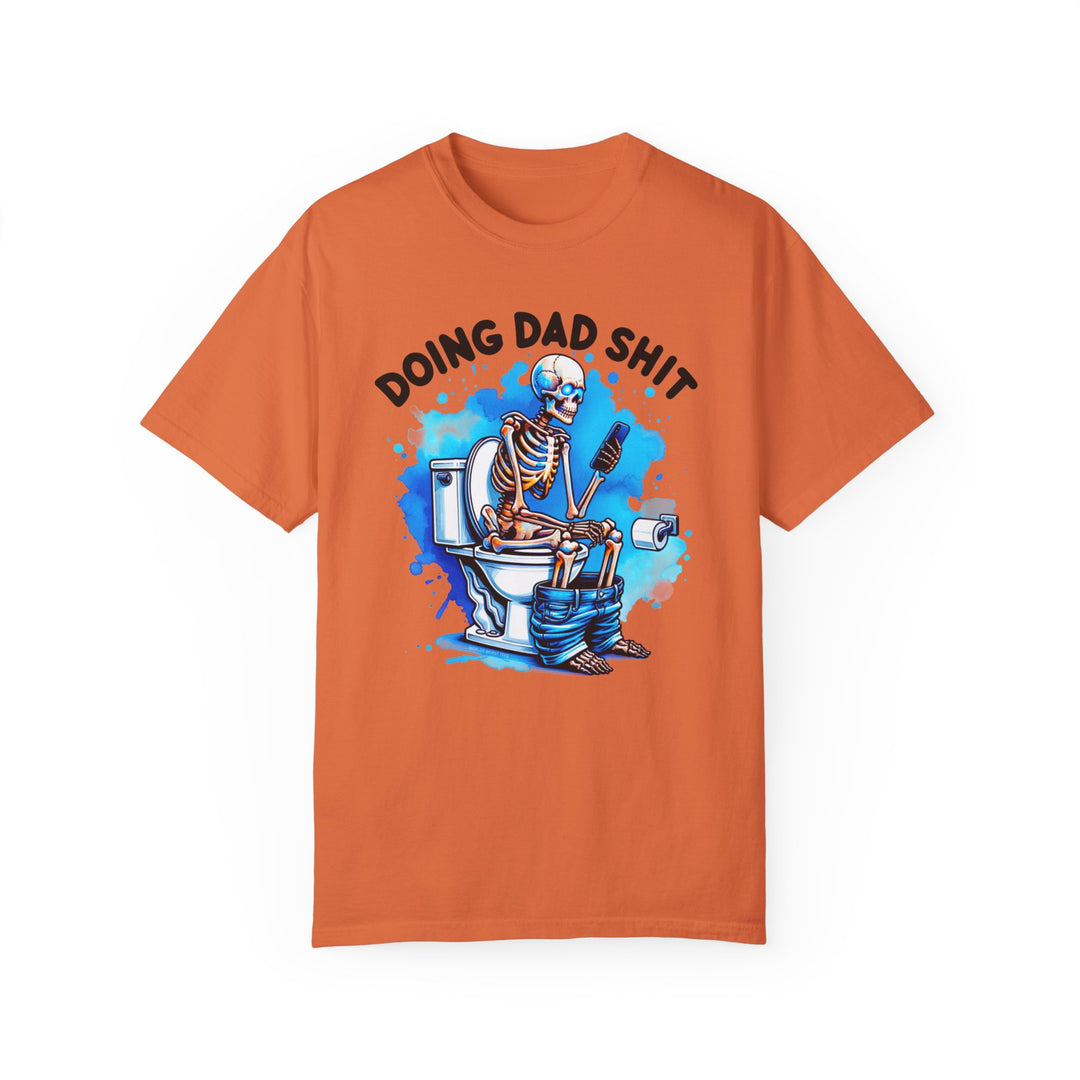 A relaxed fit, garment-dyed t-shirt featuring a skeleton on a toilet, ideal for daily wear. Made of 100% ring-spun cotton for coziness and durability. From Worlds Worst Tees, the Doing Dad Shit Tee.