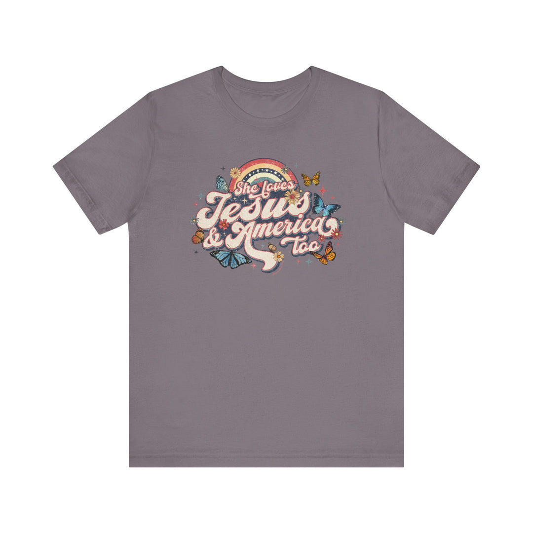 A grey She Loves Jesus and America Tee with a graphic design of butterflies and flowers on soft cotton. Unisex jersey tee with ribbed knit collars, taping on shoulders, and tear away label.