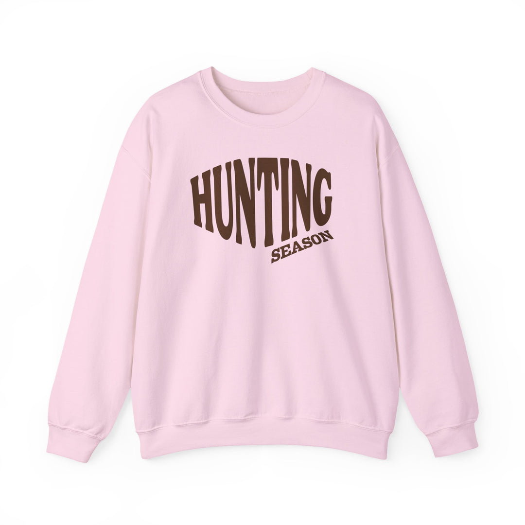 Light pink crewneck sweatshirt with HUNTING SEASON in bold brown letters, designed for comfort and style, perfect for colder months.