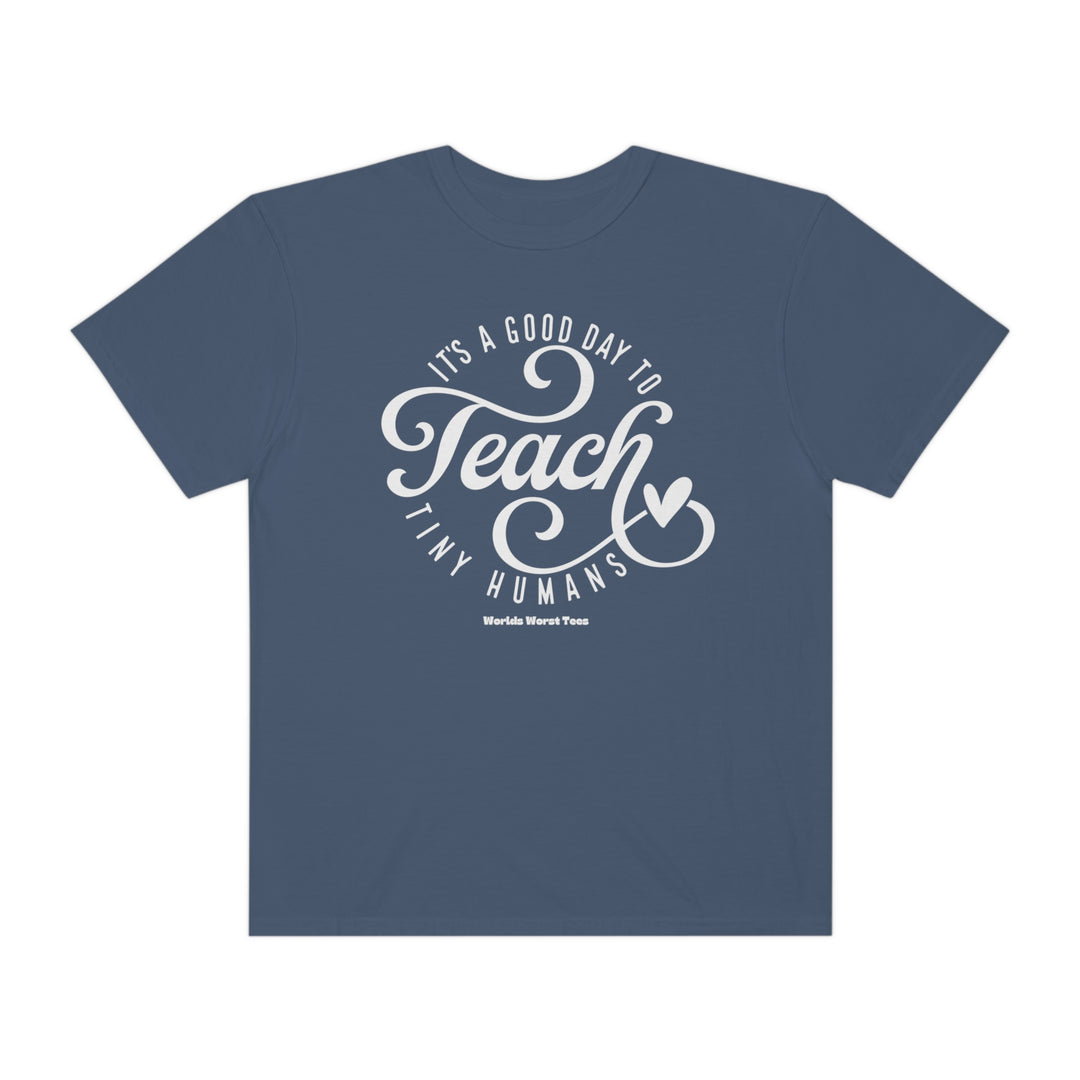 A unisex Teach Tiny Humans Tee, garment-dyed with 80% ring-spun cotton and 20% polyester. Features a relaxed fit, rolled-forward shoulder, and back neck patch. Medium-heavy fabric.