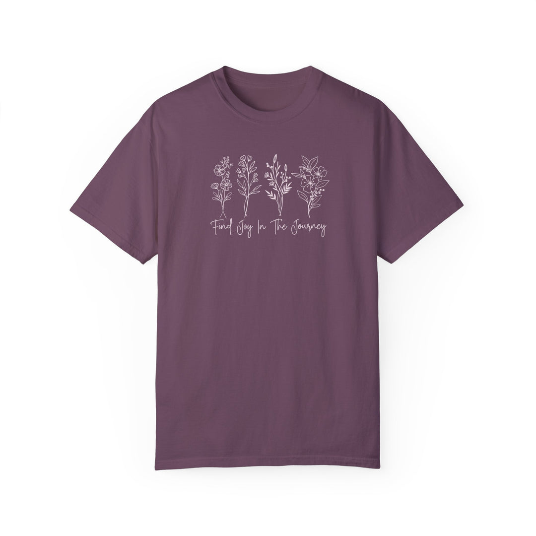 A ring-spun cotton tee titled Find Joy in the Journey Tee in purple with white text and floral design. Garment-dyed for coziness, featuring a relaxed fit and double-needle stitching for durability.