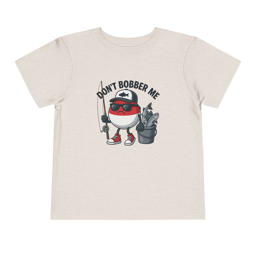 Don't Bobber Me Toddler Tee featuring a cartoon fishing bobber with a scowling face, sunglasses, fishing rod, and overflowing fish bucket, perfect for kids' playful wardrobes.
