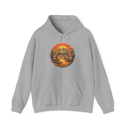 A grey heavy blend hooded sweatshirt featuring a logo with a sunset and mountains, ideal for relaxation. Made of 50% cotton and 50% polyester, with a kangaroo pocket and drawstring hood. From 'Worlds Worst Tees'.
