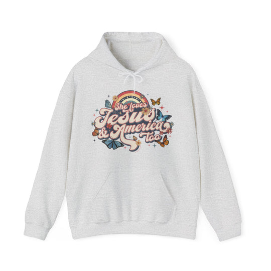 A white hooded sweatshirt featuring a graphic design of butterflies and flowers, titled She Loves Jesus and America Hoodie by Worlds Worst Tees. Unisex, heavy blend fabric with kangaroo pocket and drawstring hood.