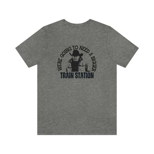 Fitted men’s tee, We're Going to Need a Bigger Train Station, featuring a man in a cowboy hat. Comfy, light, ribbed collar, roomy fit, 100% cotton. Sizes XS-3XL.