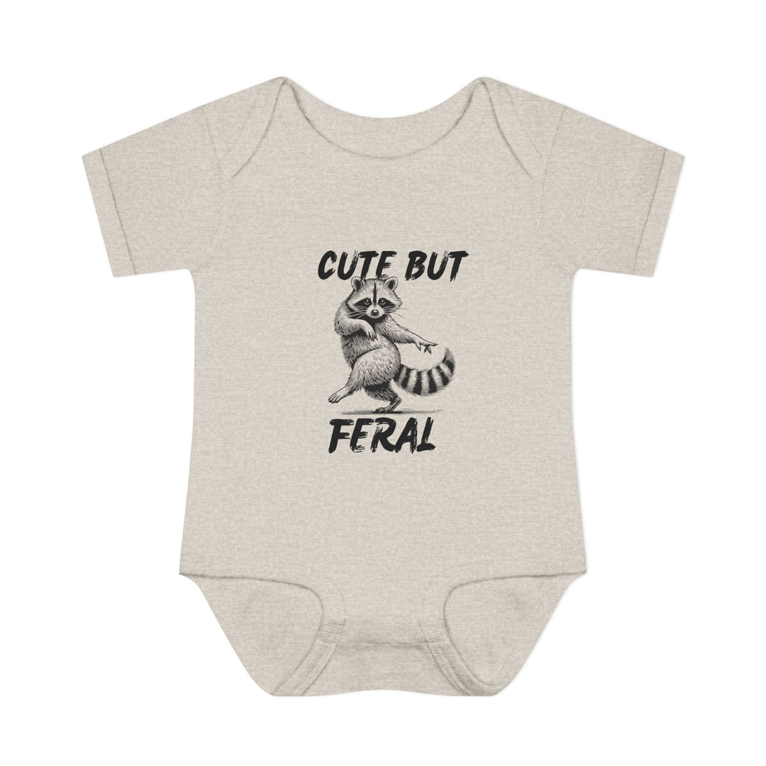 Light-heathered baby onesie with hand-drawn raccoon and CUTE BUT FERAL text, emphasizing playful design and soft, comfortable fit for infants.