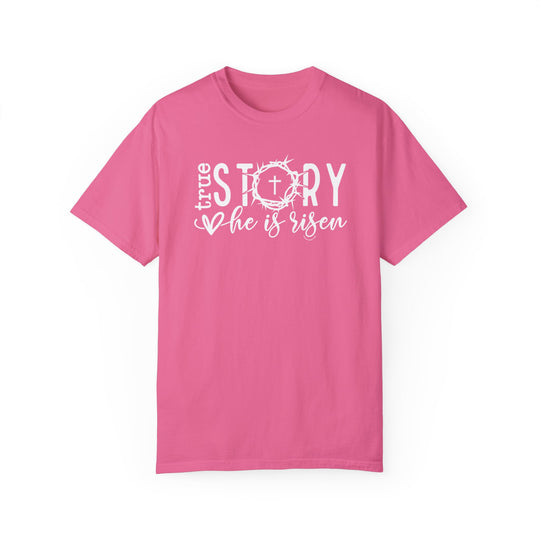 A True Story He is Risen Tee, a pink garment-dyed shirt with white text. Made of 100% ring-spun cotton, featuring a relaxed fit and double-needle stitching for durability. Ideal for daily wear.