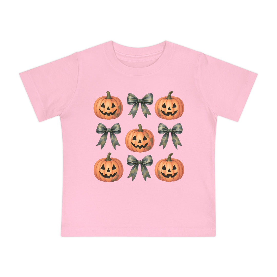Pumpkins and Bows Baby Tee: Light pink children's T-shirt with a 3x3 grid of smiling jack-o’-lanterns and camouflage-print bows, offering softness and durability for infants.