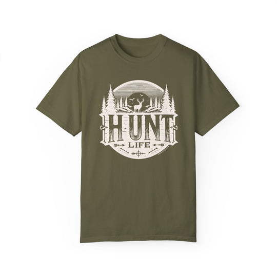 A Hunt Life Tee, featuring a green shirt with a white deer and tree logo. 100% ring-spun cotton, garment-dyed for coziness, with a relaxed fit and durable double-needle stitching.