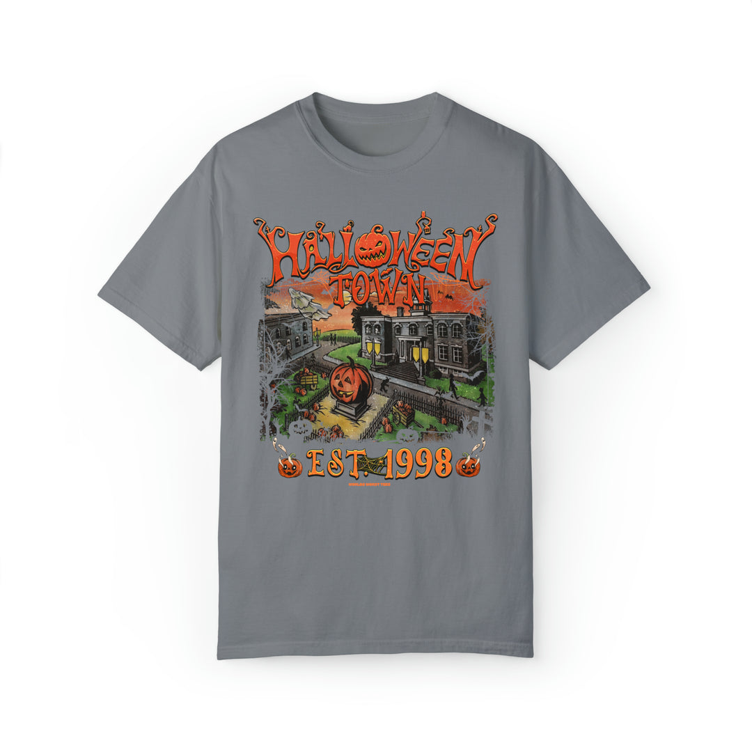 A grey t-shirt featuring a whimsical Halloweentown design with a pumpkin, a train, a house, and spooky elements. Unisex, relaxed fit with ring-spun cotton and polyester blend. From Worlds Worst Tees.