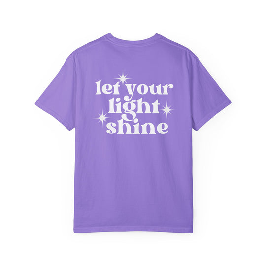 A relaxed fit Let Your Light Shine Tee, a purple shirt with white text, made of 100% ring-spun cotton. Double-needle stitching for durability, no side-seams for a tubular shape. Sizes S to 3XL.