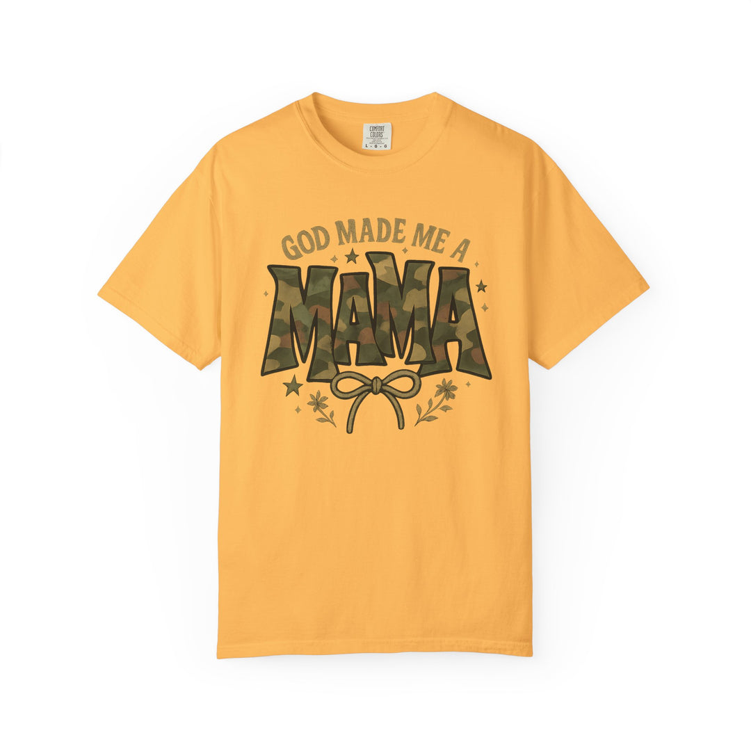 Mustard-yellow tee by Comfort Colors with GOD MADE ME A MAMA in camo font, featuring a bow, floral sprigs, and stars.