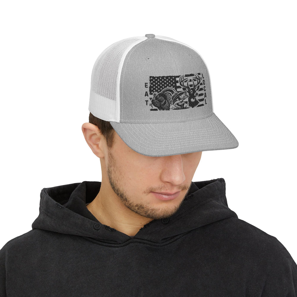 Young man models the Eat Local Snapback Trucker Cap featuring wildlife silhouettes and American flag graphic, paired with a dark hoodie.