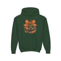 Jackie O Youth Hoodie: Dark green hoodie with a jack-o’-lantern featuring orange and camouflage segments, topped with an orange bow, and a kangaroo pocket.