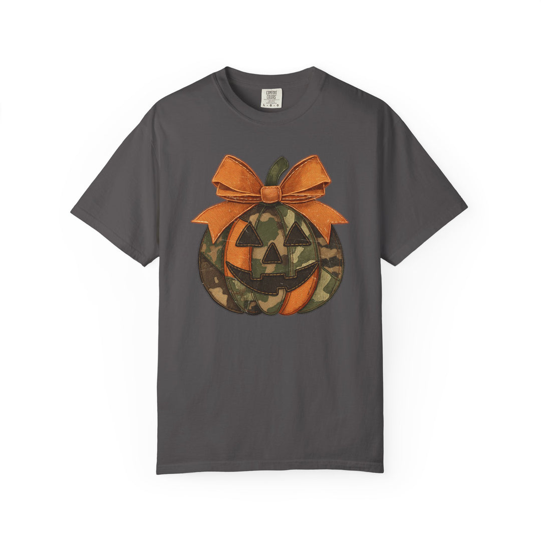 Jackie O Tee: Dark gray Comfort Colors T-shirt featuring a stylized jack-o’-lantern with camouflage panels and orange bow, ideal for casual wear.