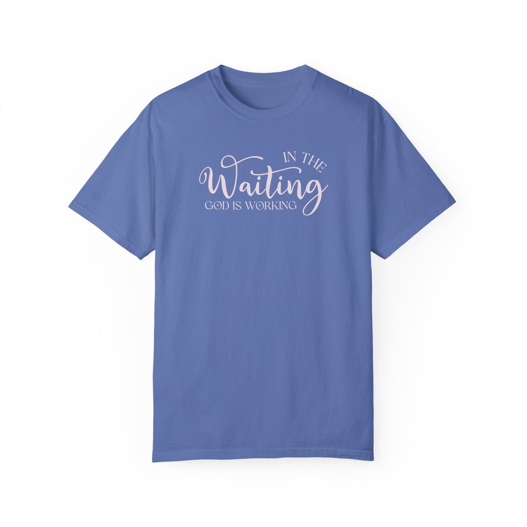 Relaxed fit God is Working Tee, garment-dyed in blue with white text. 100% ring-spun cotton, soft-washed for coziness, double-needle stitching for durability, no side-seams for shape retention. Sizes S-4XL.