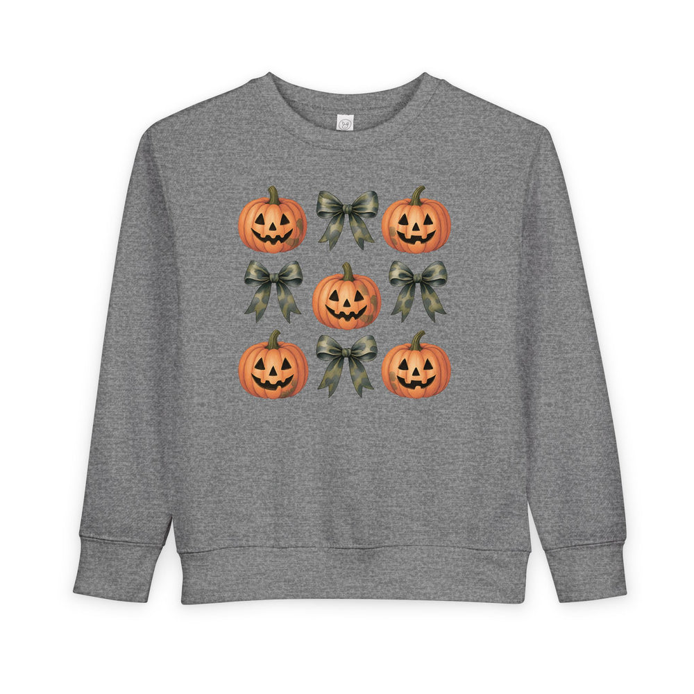Pumpkins and Bows Toddler Crew: A heather-gray sweatshirt featuring a 3x3 grid of smiling jack-o-lanterns and camouflage-patterned ribbon bows, designed for comfort and style.