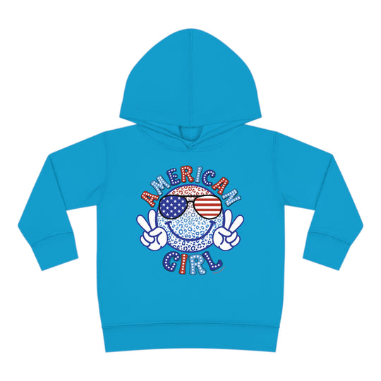 American Girl Toddler Hoodie featuring a smiley face with sunglasses and a peace sign. Jersey-lined hood, cover-stitched details, and side seam pockets for durability and coziness. Designed in 60% cotton, 40% polyester blend.