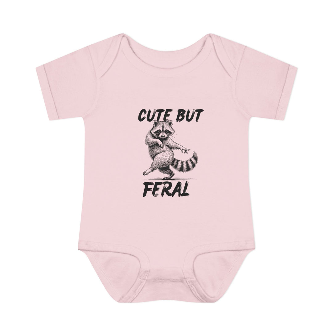 Light-pink Cute But Feral onesie featuring a sketch of a pointing raccoon, designed for comfort with soft, 100% combed ringspun cotton and convenient lap shoulders.