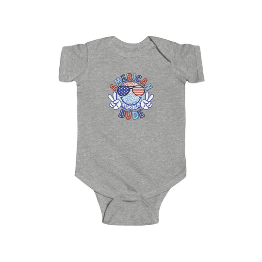 American Dude Onesie, grey baby bodysuit featuring a peace sign cartoon character logo. Soft 100% cotton fabric, ribbed knit bindings, and plastic snaps for easy changing. Ideal for infants, sizes 0-24M.