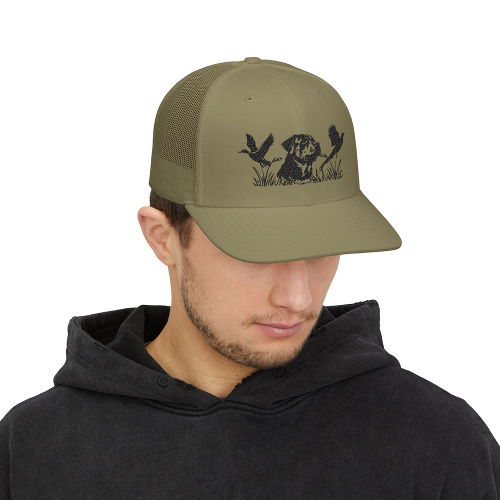 Young man wearing the Bird Hunting Snapback Trucker Cap, featuring an embroidered hunting dog and ducks design, showcasing its stylish mesh-back and pre-curved visor.