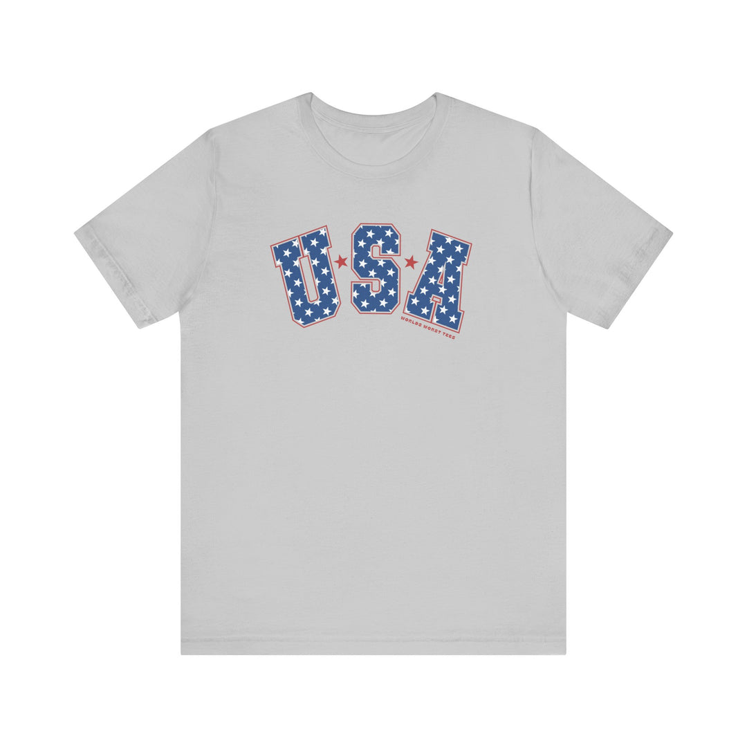 A USA Tee, unisex jersey shirt with red and blue letters and stars. Airlume combed cotton, ribbed knit collar, and retail fit. Sizes XS-3XL. Characteristics: soft fabric, quality print, durable seams.