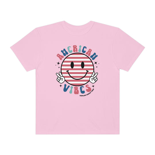 American Vibes Tee: A pink t-shirt featuring a smiley face and peace sign. Made of 100% ring-spun cotton with a relaxed fit for daily comfort. Durable double-needle stitching and seamless design for lasting quality.