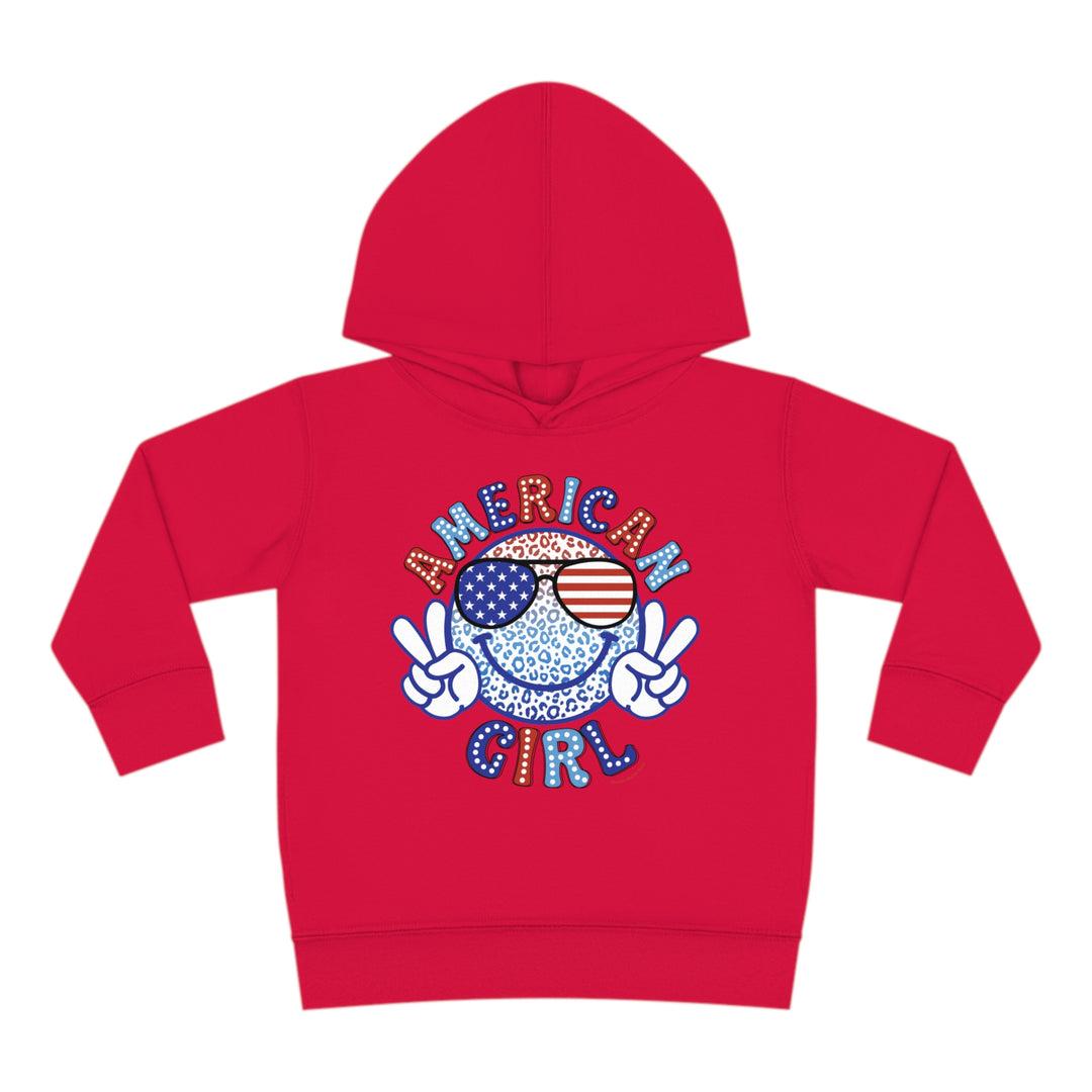 American Girl Toddler Hoodie featuring a red design with a smiley face and sunglasses. Jersey-lined hood, cover-stitched details, and side pockets for durability and coziness. Ideal for kids aged 2 to 6.