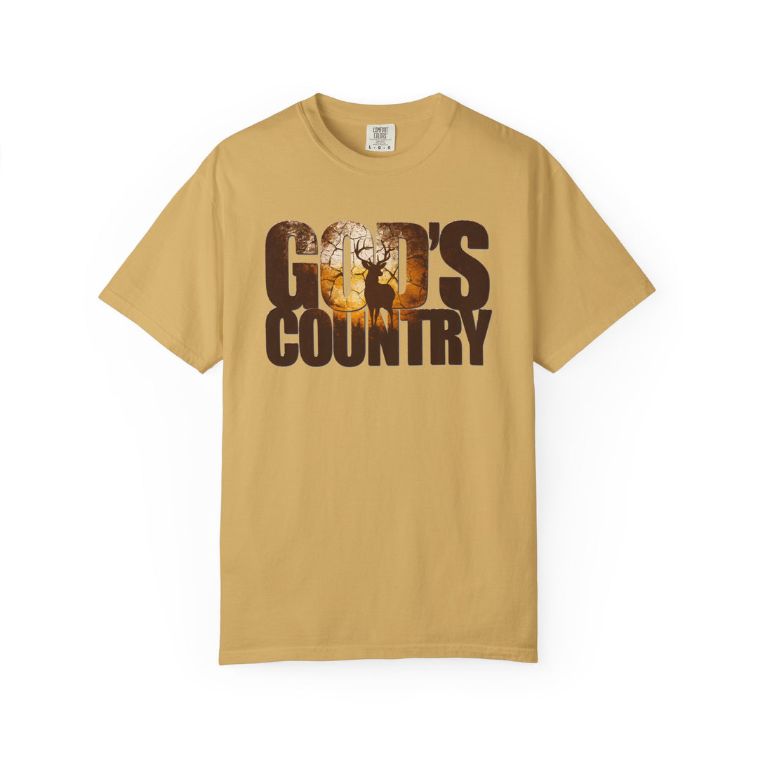 Mustard-colored God's Country Tee featuring a sunrise forest scene with a stag silhouette within the letters, reflecting a trendy, graphic design.
