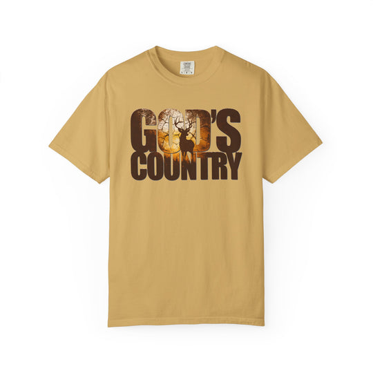 Mustard-colored God's Country Tee featuring a sunrise forest scene with a stag silhouette within the letters, reflecting a trendy, graphic design.