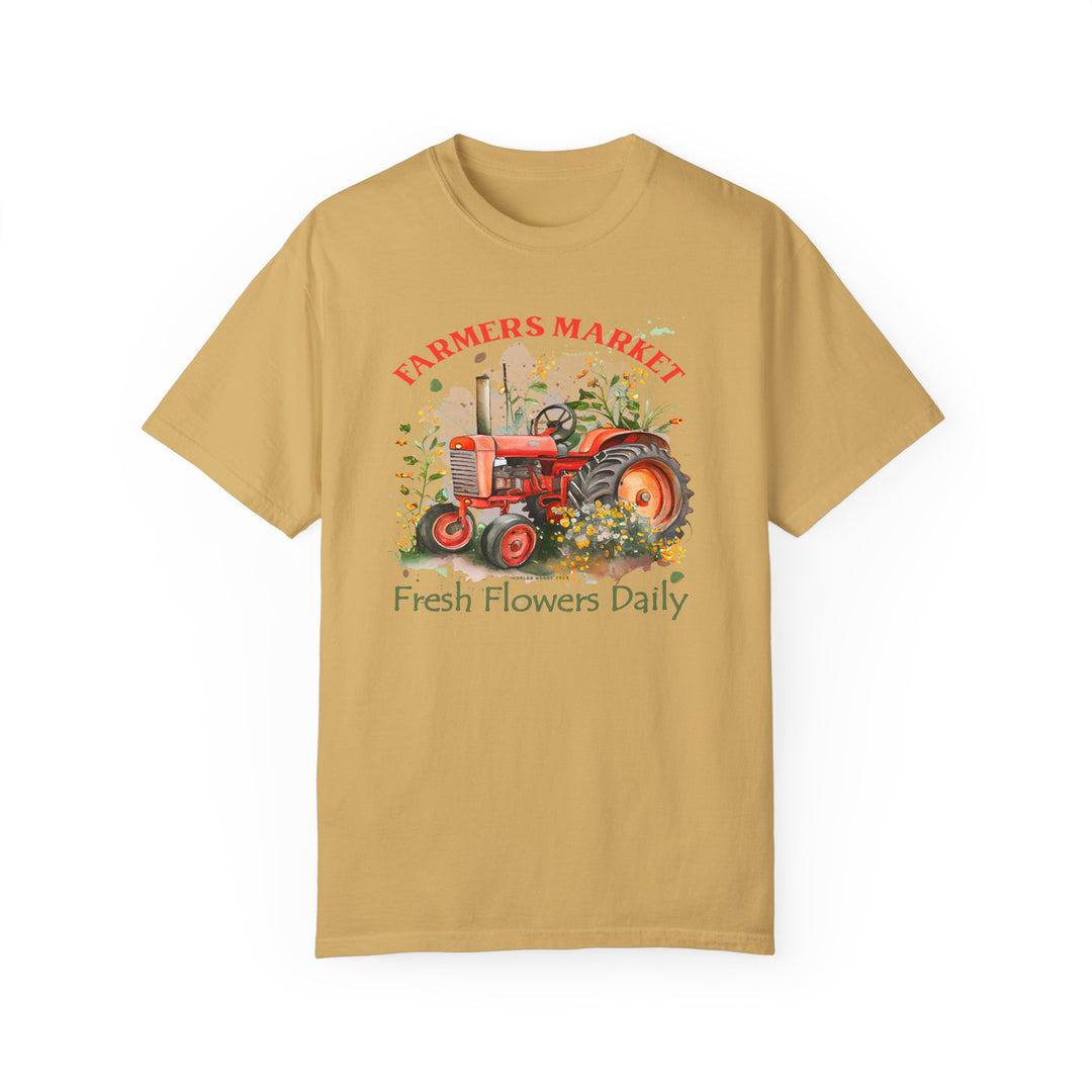 Alt text: Fresh Flowers Tee: Tan t-shirt featuring a tractor and flowers design. 100% ring-spun cotton, garment-dyed for coziness. Relaxed fit, double-needle stitching for durability, seamless sides for a tubular shape.