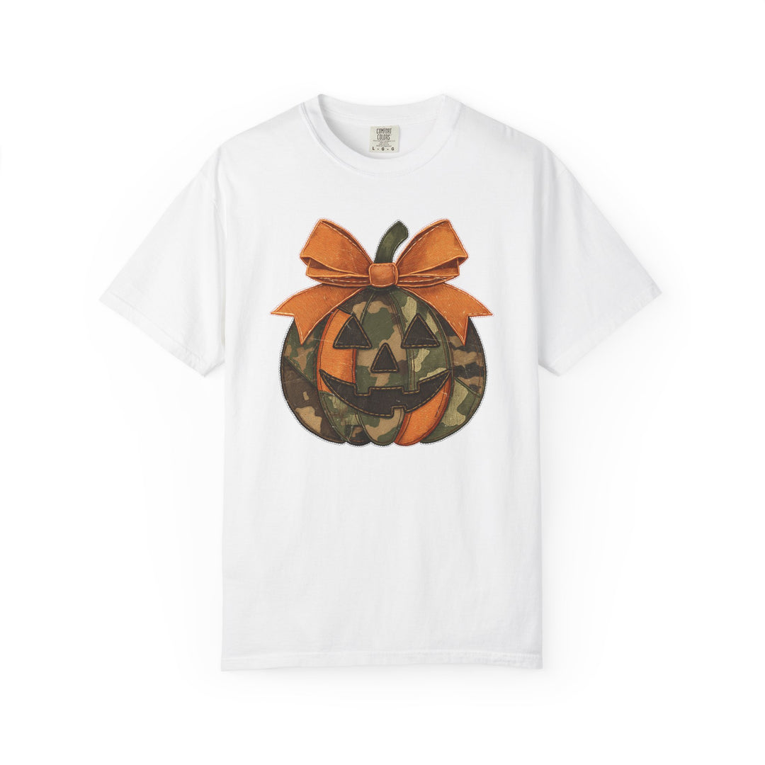 Jackie O Tee featuring a jack-o-lantern graphic with alternating orange and camo segments, topped with an oversized bow, on a white short-sleeve T-shirt.