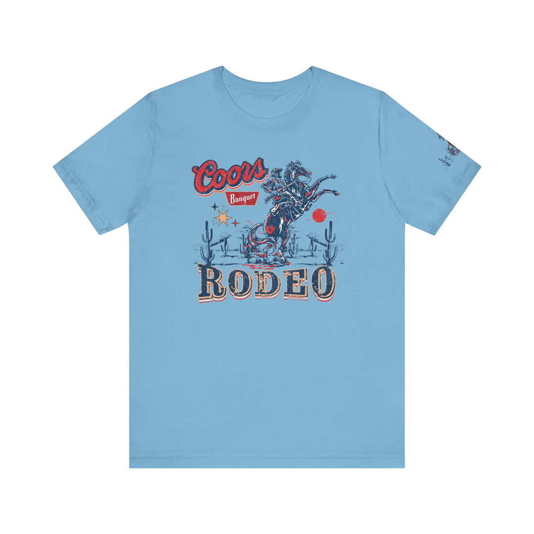 Coors Rodeo Tee: A blue t-shirt featuring a cowboy graphic on horseback. Unisex jersey tee with ribbed knit collars, 100% cotton, and tear-away label. Fits true to size.