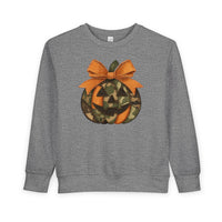 Heather-gray Jackie O Toddler Crew sweatshirt with a stylized jack-o’-lantern graphic, featuring orange-camouflage panels and a stitched-look bow, designed for toddlers.