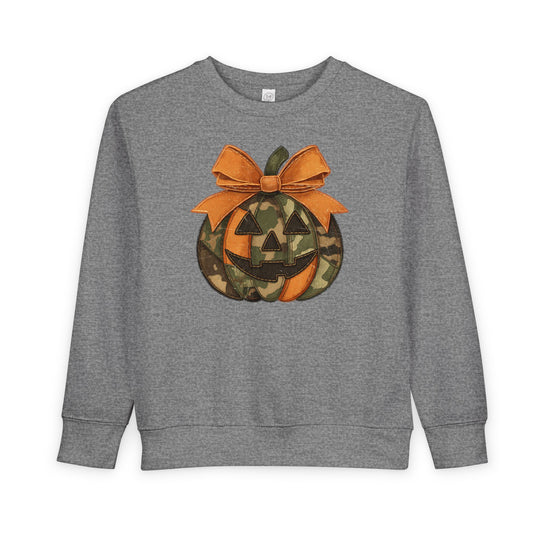 Heather-gray Jackie O Toddler Crew sweatshirt with a stylized jack-o’-lantern graphic, featuring orange-camouflage panels and a stitched-look bow, designed for toddlers.