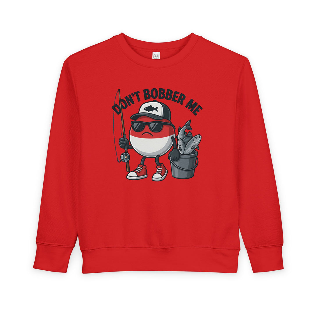 Don't Bobber Me Toddler Crew features a playful fishing bobber character with sunglasses, baseball cap, holding a rod and fish bucket, on a cozy sweatshirt.
