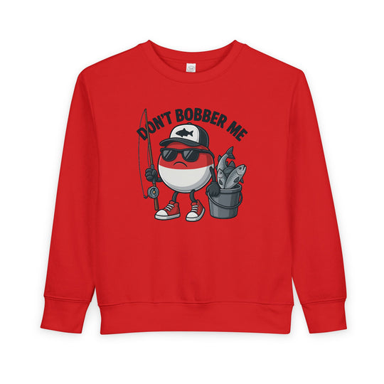 Don't Bobber Me Toddler Crew features a playful fishing bobber character with sunglasses, baseball cap, holding a rod and fish bucket, on a cozy sweatshirt.