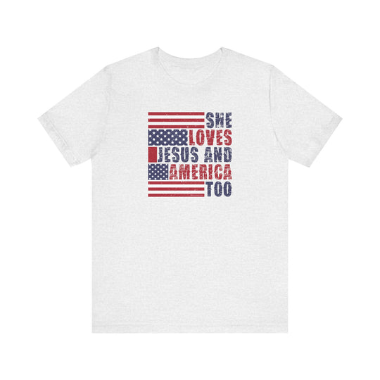 A beloved She Loves Jesus and America Tee, a white shirt with red and blue text. Unisex jersey tee with ribbed knit collars, taping on shoulders, and tear-away label. 100% Airlume combed cotton, retail fit.