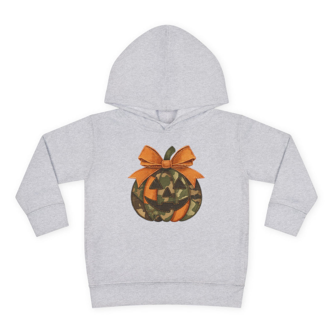 Jackie O Toddler Hoodie: Light-gray children's sweatshirt with a jack-o’-lantern graphic featuring orange and camouflage panels, topped with a large orange bow.