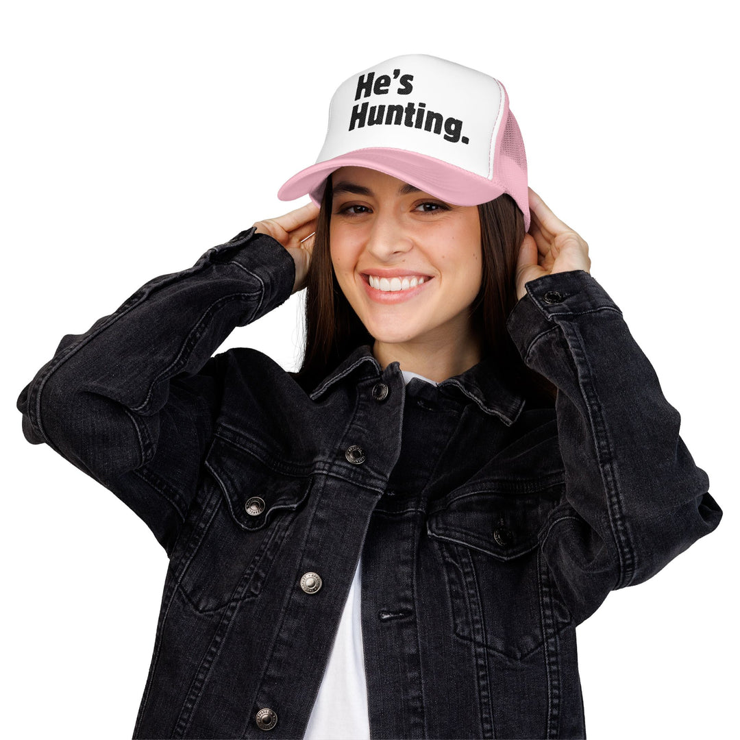 Young woman wearing the He's Hunting Foam Trucker Hat, adjusting the cap with a smile, showcasing its structured design and bold embroidery.