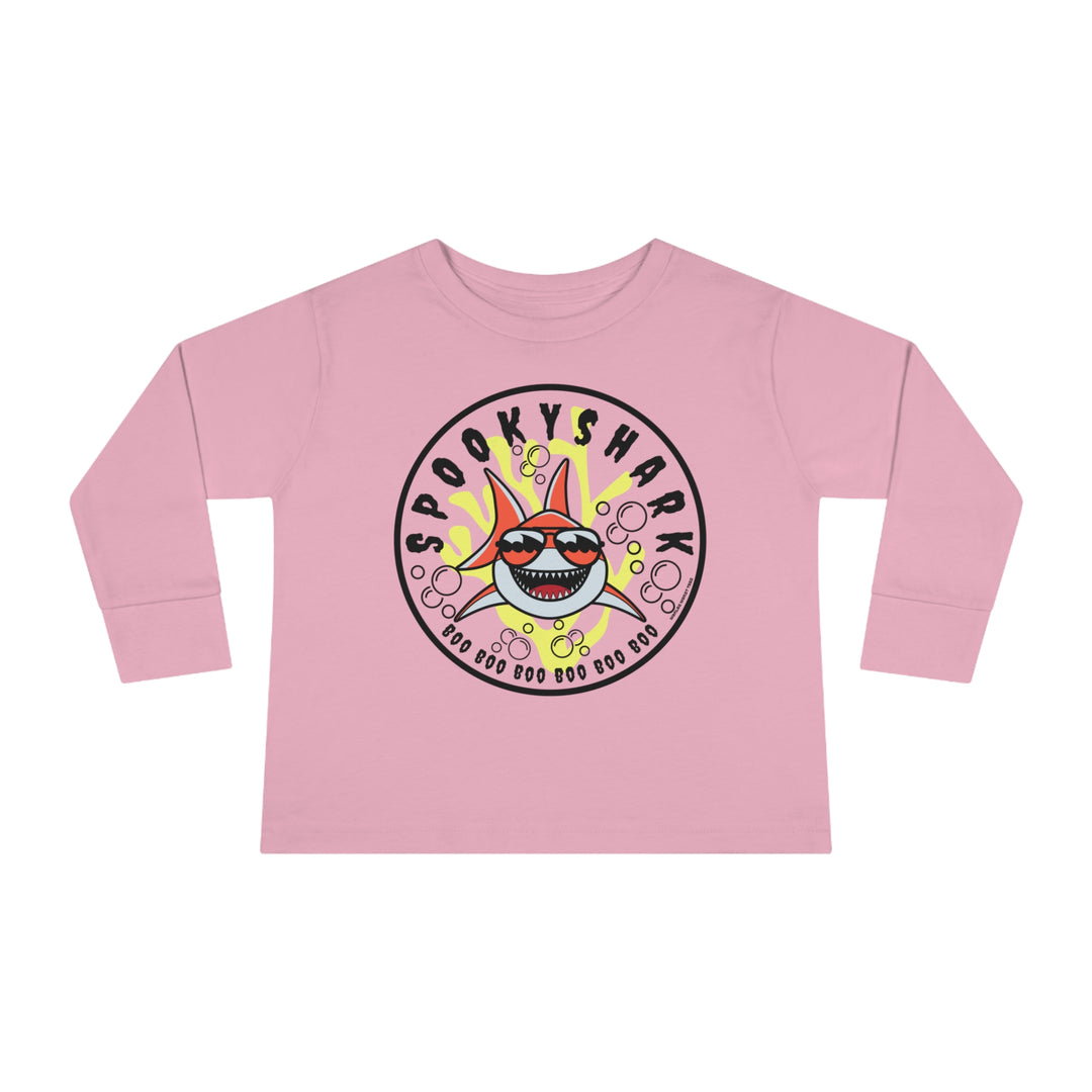 A spooky shark cartoon character adorns a pink toddler long-sleeve tee from Worlds Worst Tees. Made of 100% cotton, featuring ribbed collar and shoulder-to-shoulder taping for durability and comfort.