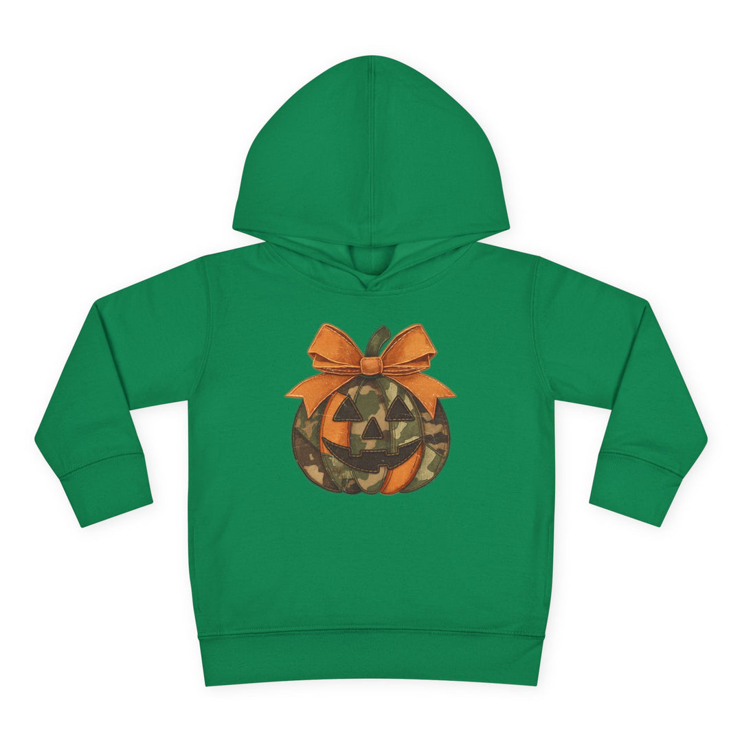 Jackie O Toddler Hoodie: Green children's hoodie featuring a camo-patterned jack-o’-lantern graphic with a bow, designed for comfort with jersey-lined hood and side pockets.