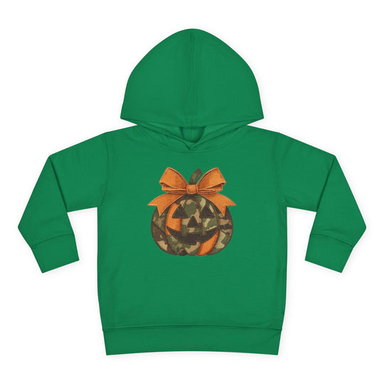 Jackie O Toddler Hoodie: Green children's hoodie featuring a camo-patterned jack-o’-lantern graphic with a bow, designed for comfort with jersey-lined hood and side pockets.