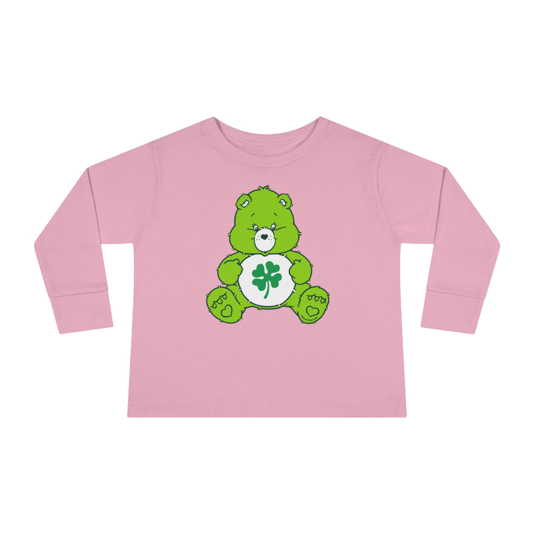 A Lucky Bear Toddler Long Sleeve Tee featuring a pink shirt with a green cartoon bear and clover. Made of 100% combed ringspun cotton, with topstitched ribbed collar for durability and comfort. Toddler unisex fit.